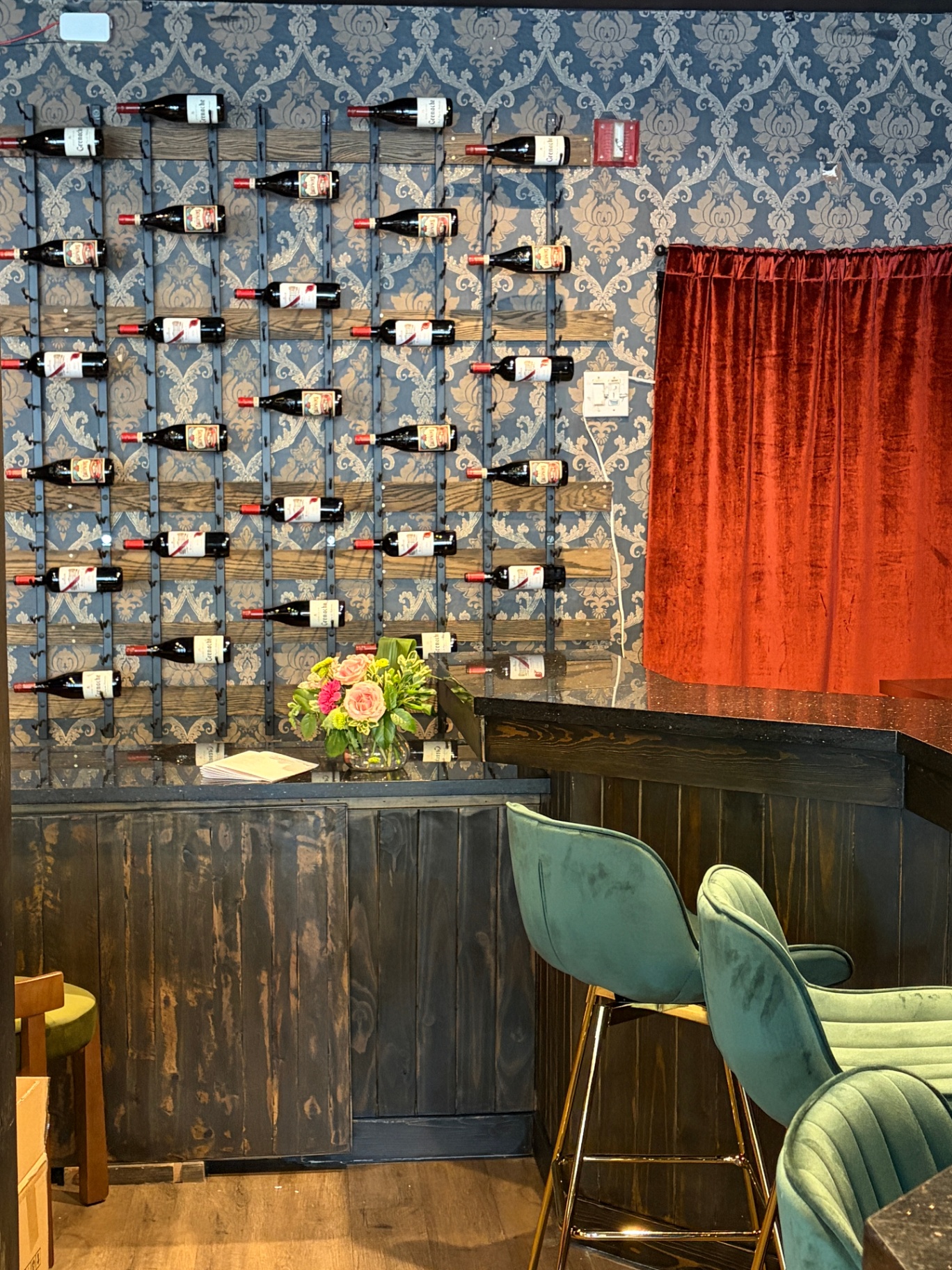 Wall of curated wine bottles on damask wallpaper